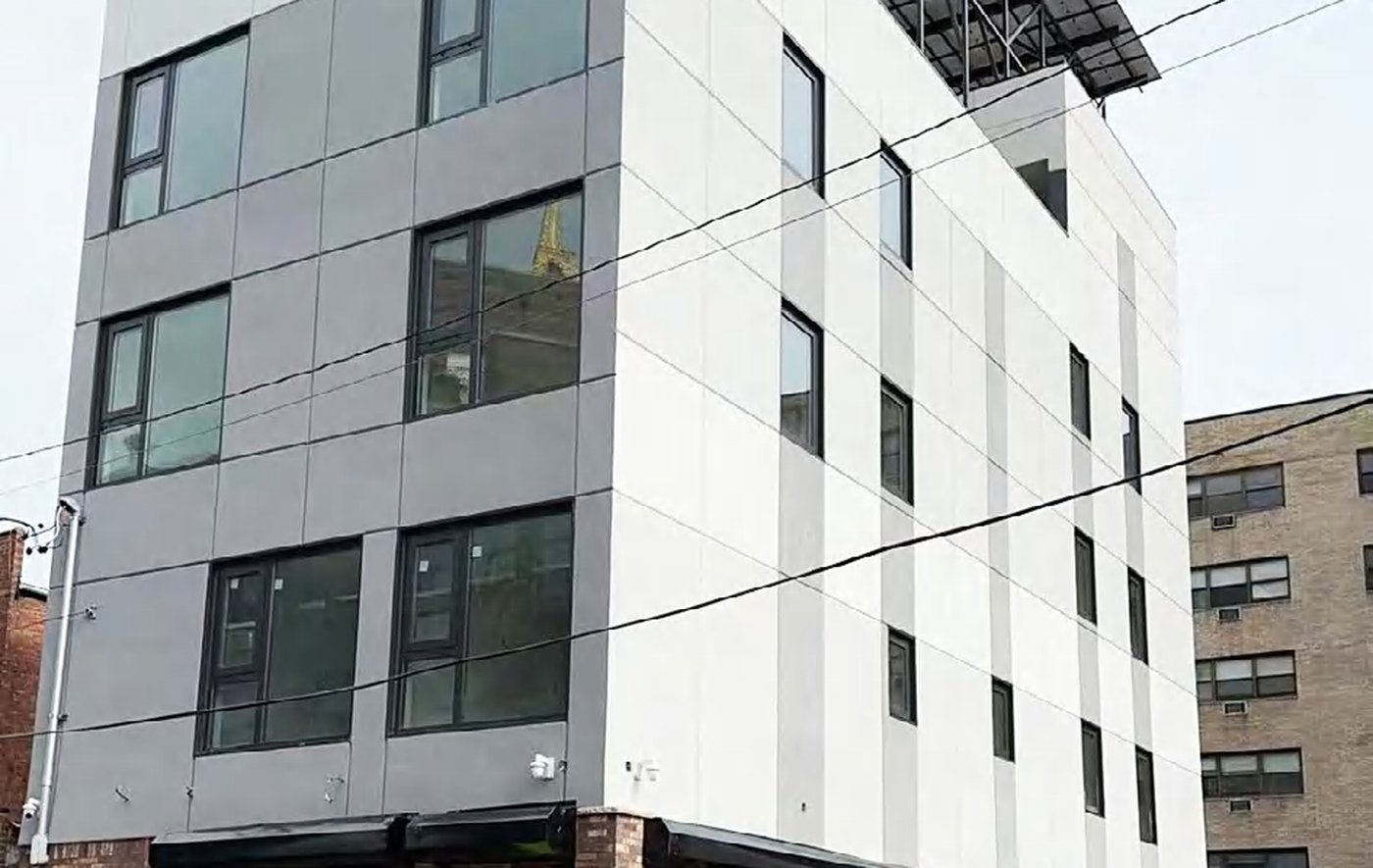 Mid-rise apartment building with aluminium windows on a US street — the market that files a tilt and turn sash under its own operator type