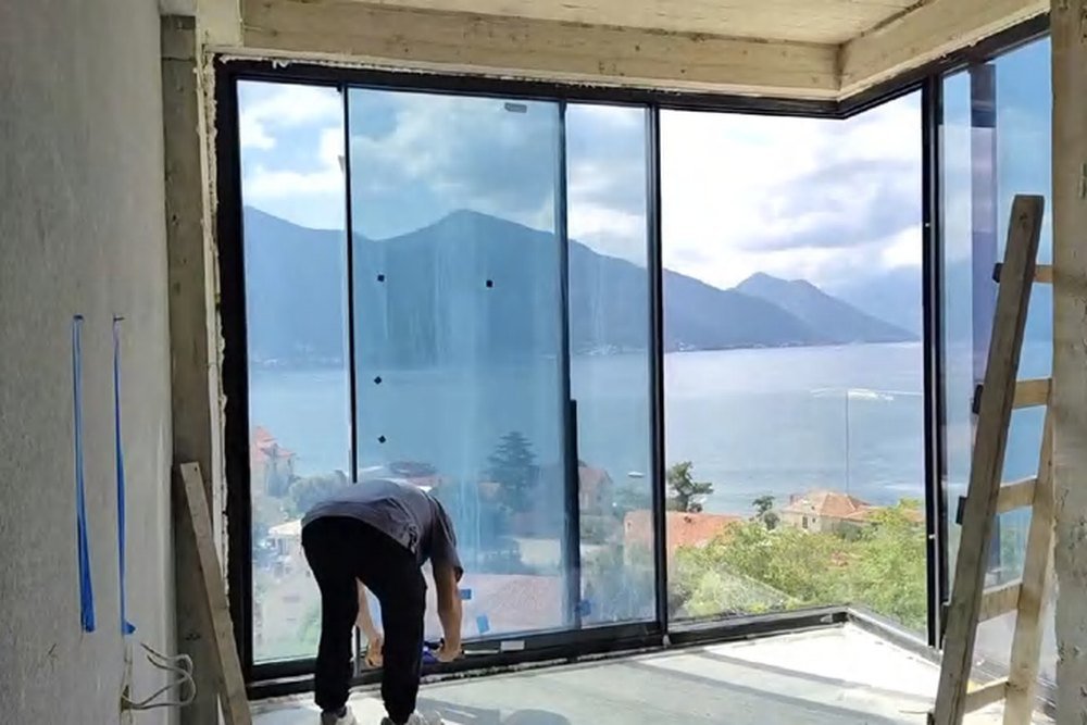 A concrete and glass hillside villa in Montenegro stepping down a wooded slope above the water