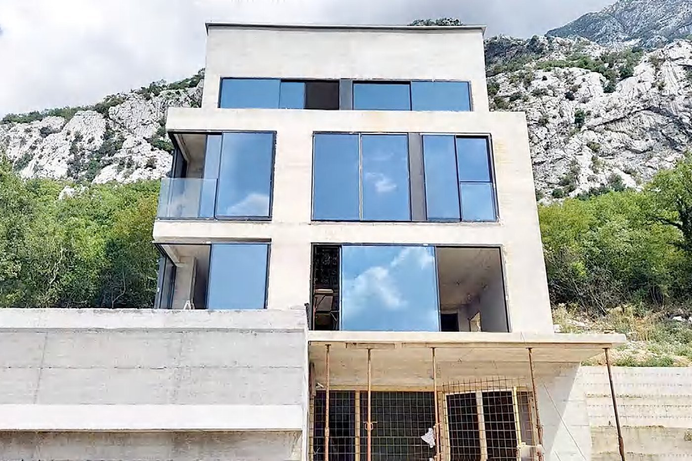 A concrete and glass hillside villa in Montenegro stepping down a wooded slope above the water