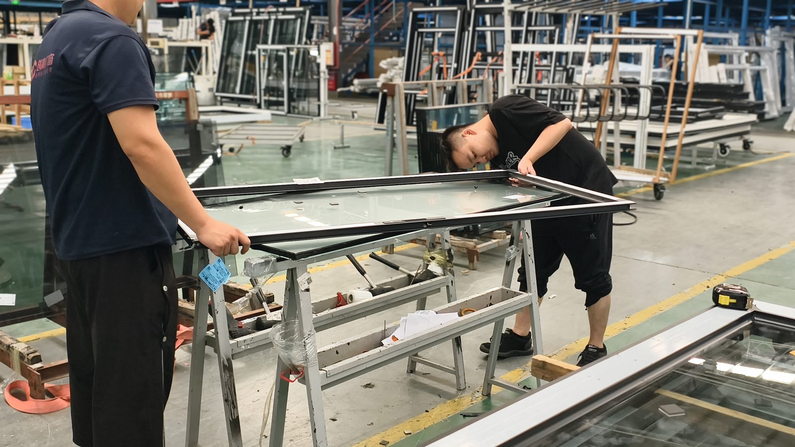 Two workers lifting a glazed sash and inspecting the glass edge