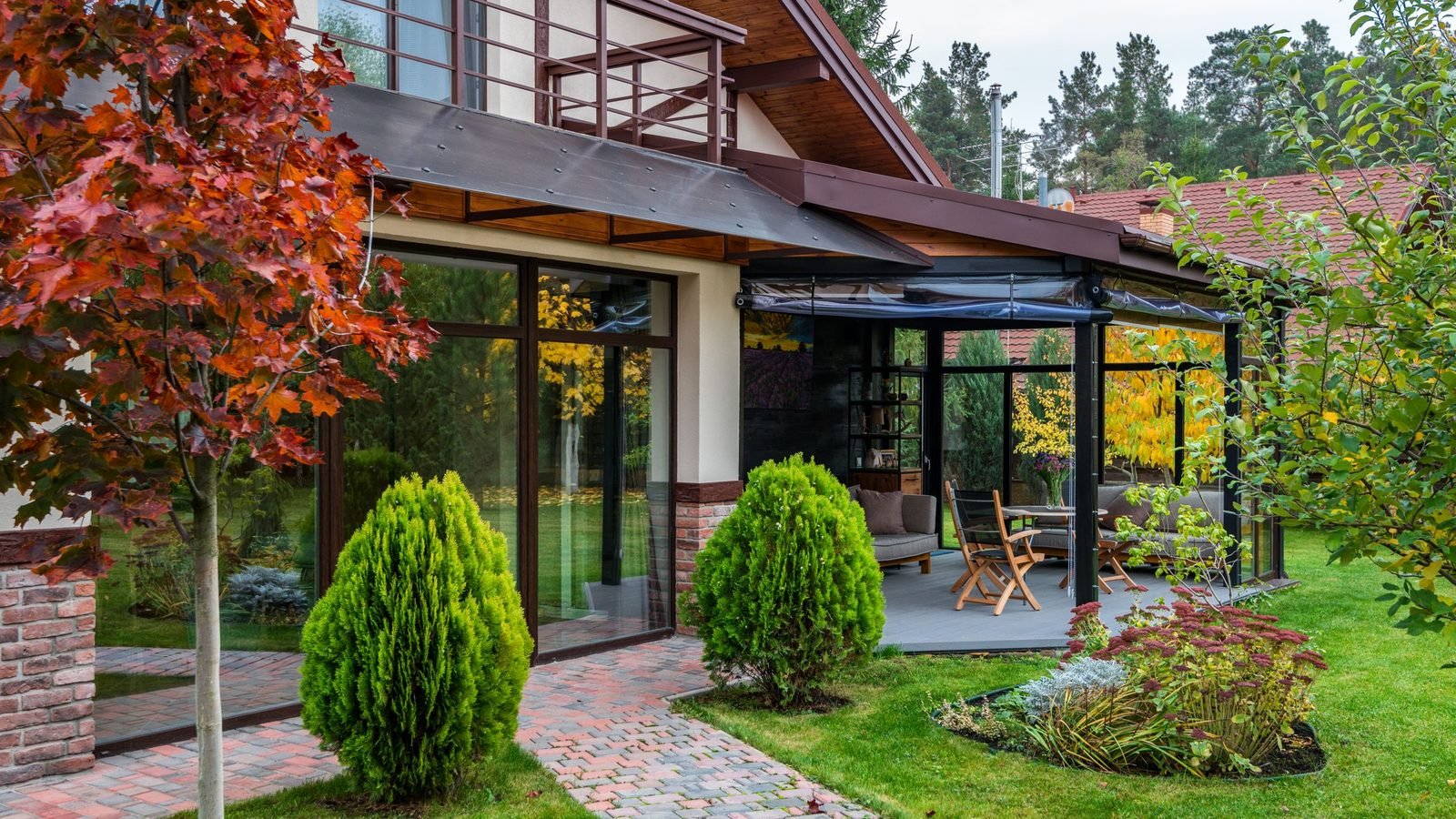 Modern house elevation with full-height glazing, the double-leaf door pair opening onto a garden terrace