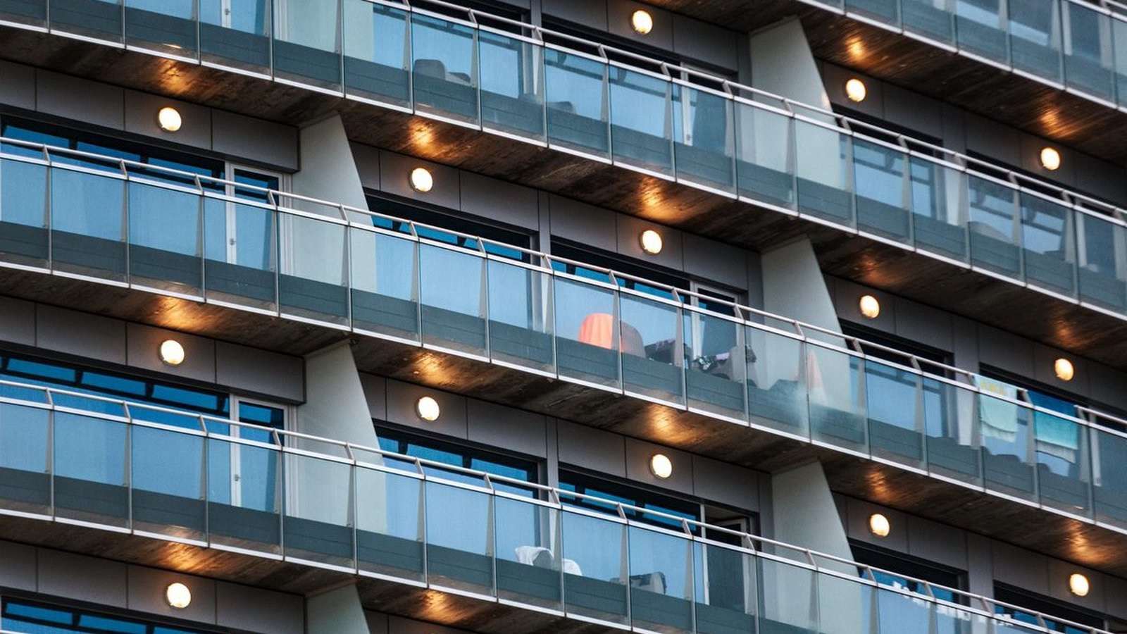Glass balustrades on the balconies of a residential block, the panels set between the floor slabs