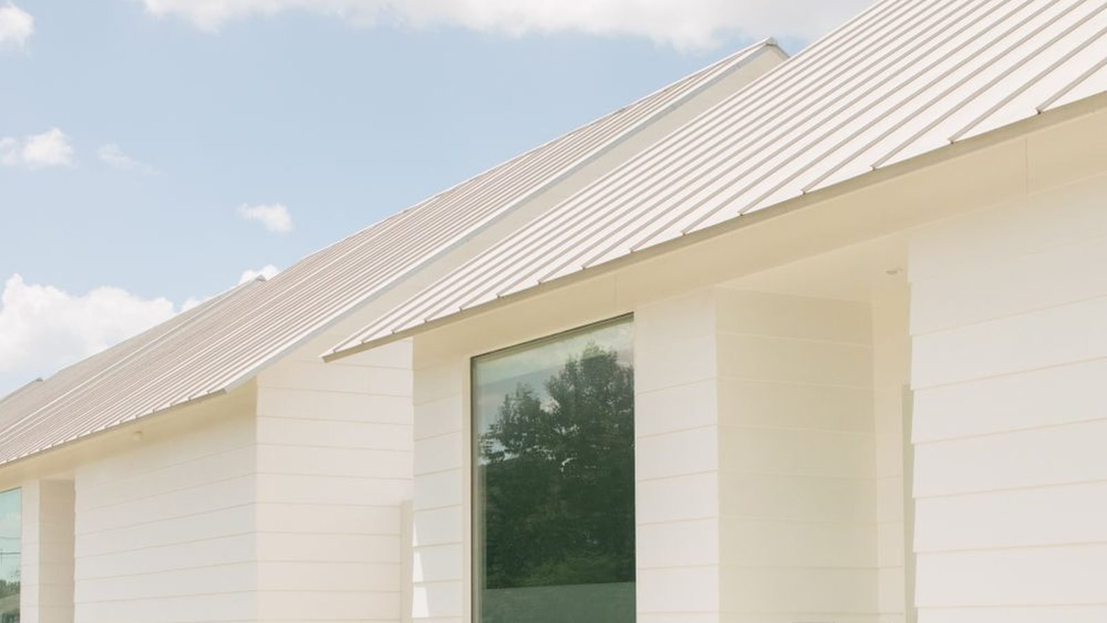 A white suburban house with large glazing under a clear sky, the Texas inland elevation