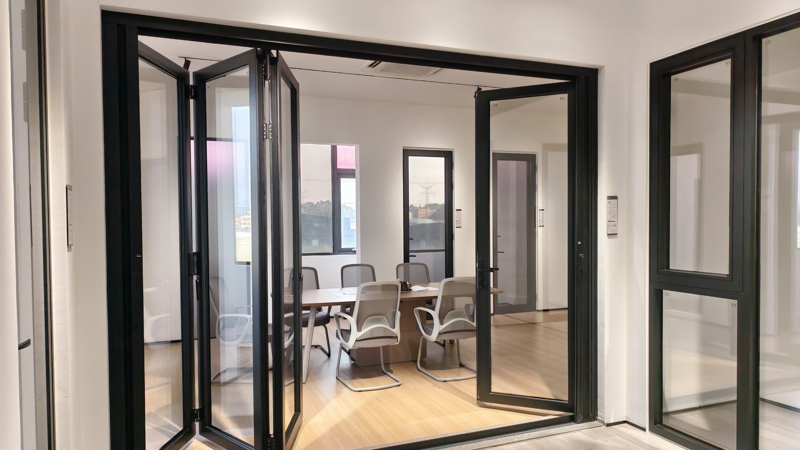 Black-framed bi-fold and hinged doors standing open to a bright interior