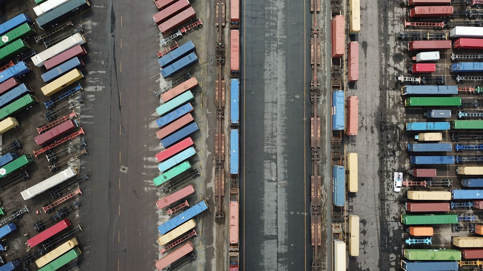 An aerial view of a container terminal, rows of boxes parked between rail lines