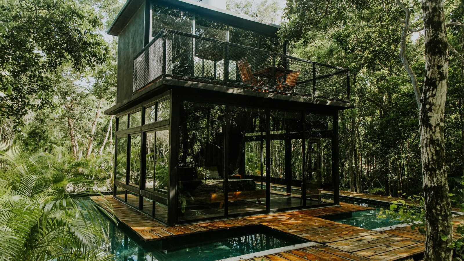 A two-storey glass pavilion in tropical planting, the lower floor fixed glazing set floor to ceiling