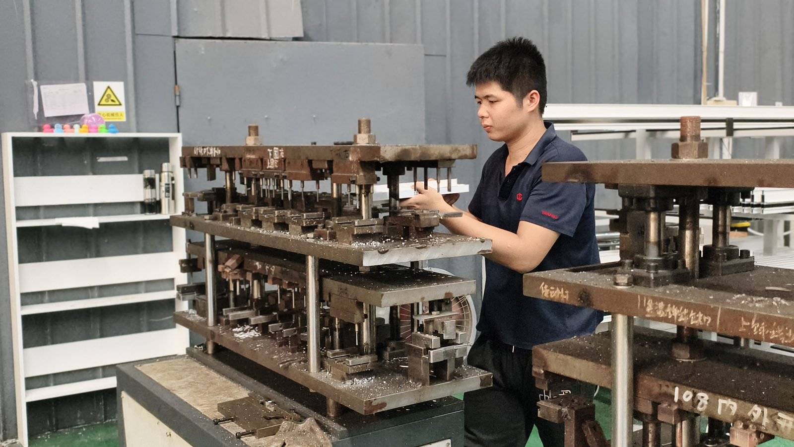 Worker operating a punch press with a corner bracket die