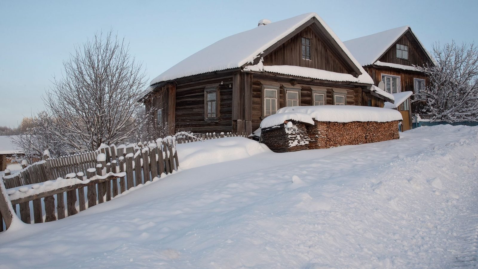 A timber house in deep winter snow, a row of small windows set in the long wall