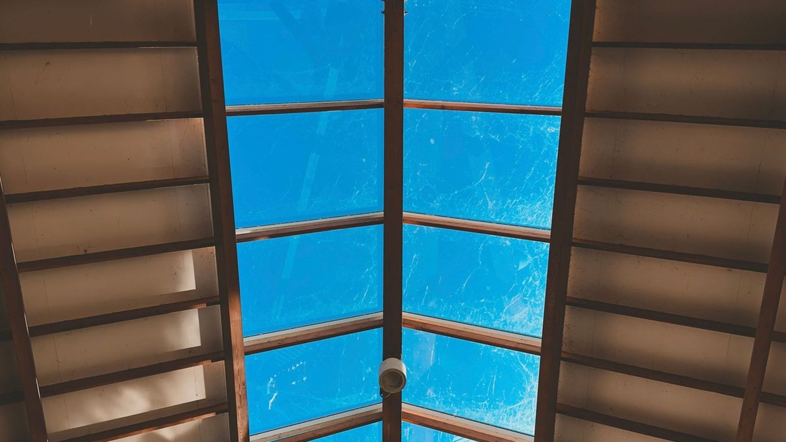A glazed roof aperture seen from inside, the sky filling the opening between two pitched ceiling planes