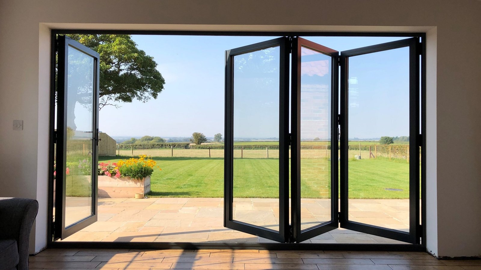 Full-height black folding glass doors open to an exposed terrace