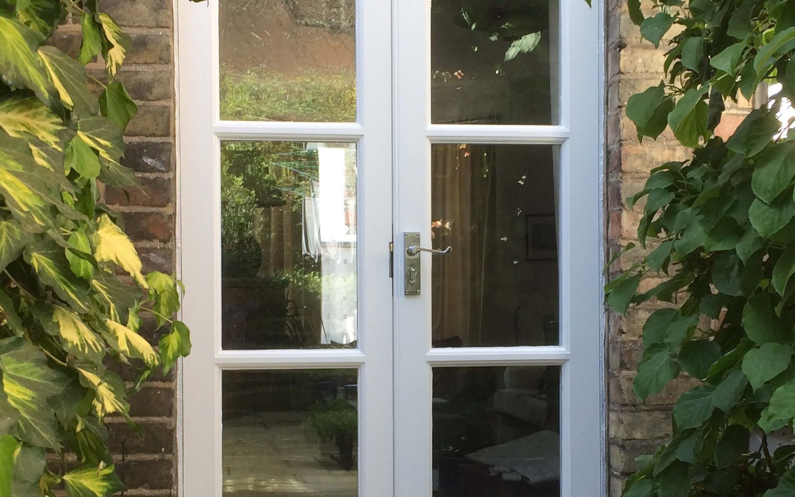 White glazed door on a planted brick entrance