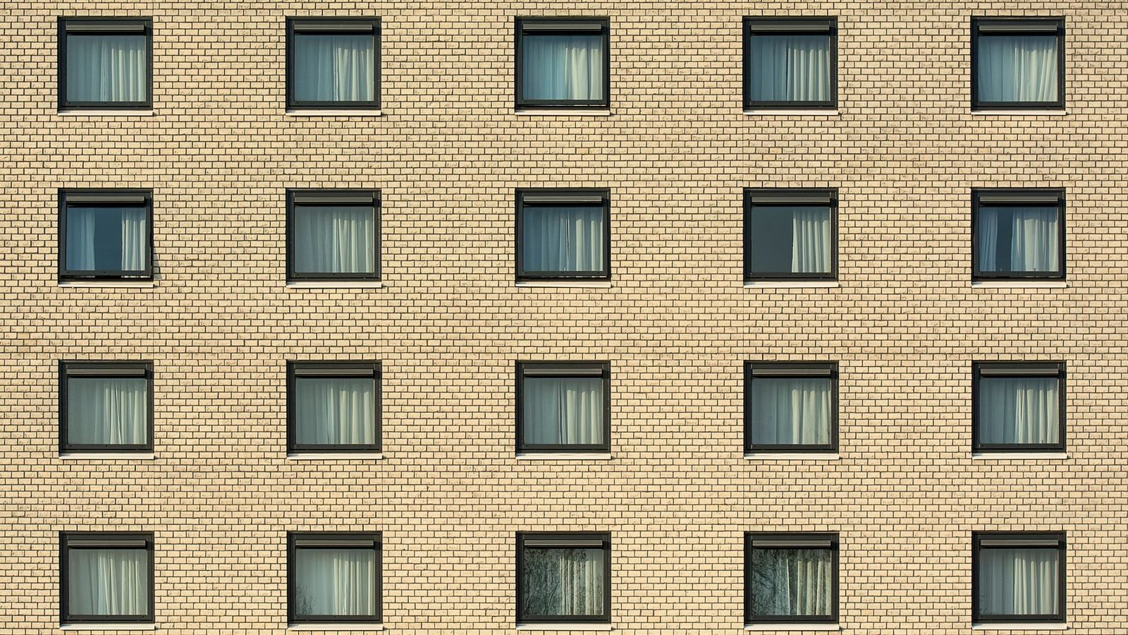 A brick facade with a grid of identical windows, four rows deep