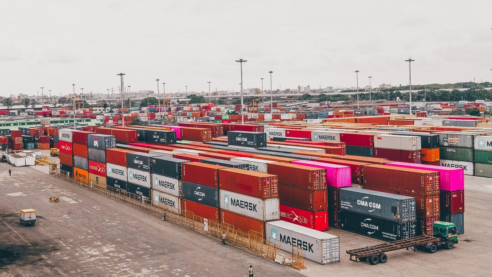 Stacked shipping containers in a container yard — the unit a wholesale window order is actually planned against